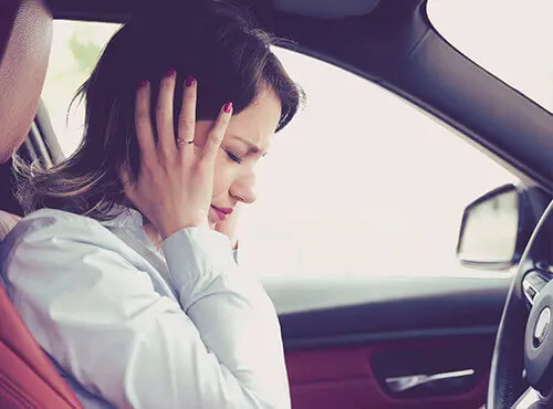 En kvinde forsøger at beskytte sig selv mod støj i bilen.
