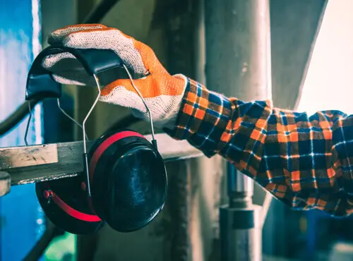 En arbejder bruger høreværn for at beskytte sig selv mod en højlydt maskine.