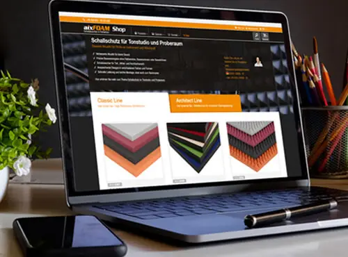 En laptop viser aixFOAMs online shop med lydabsorbere og et udvalg af støjværnsprodukter.